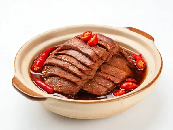 香辣红烧牛肉被整齐切肉片呈现在陶罐中,表面裹着红亮酱汁,周围点缀着鲜红辣椒。