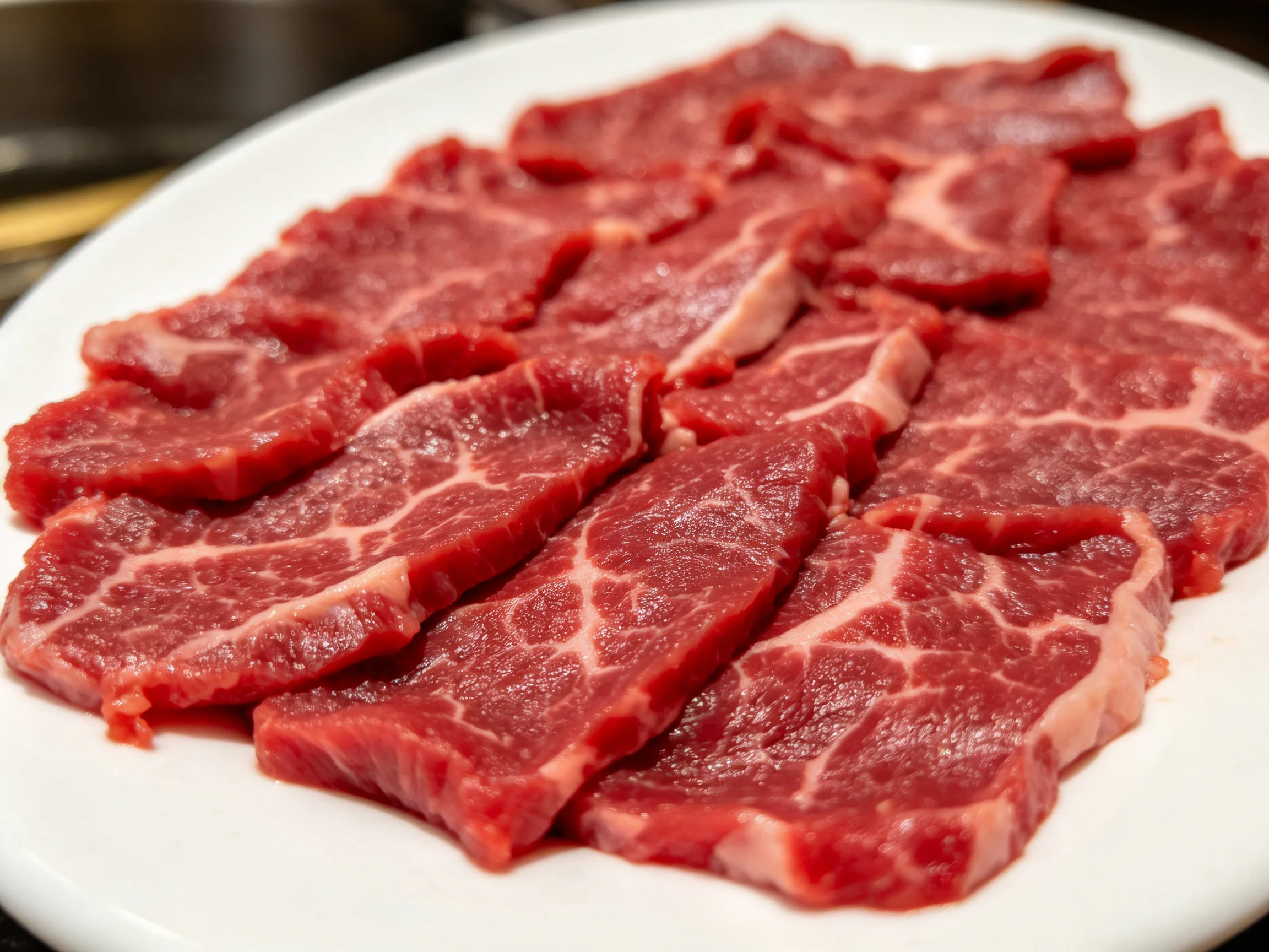 牛里脊肉切片呈现出鲜艳红色泽,脂肪纹理清晰,是优质的火锅食材。