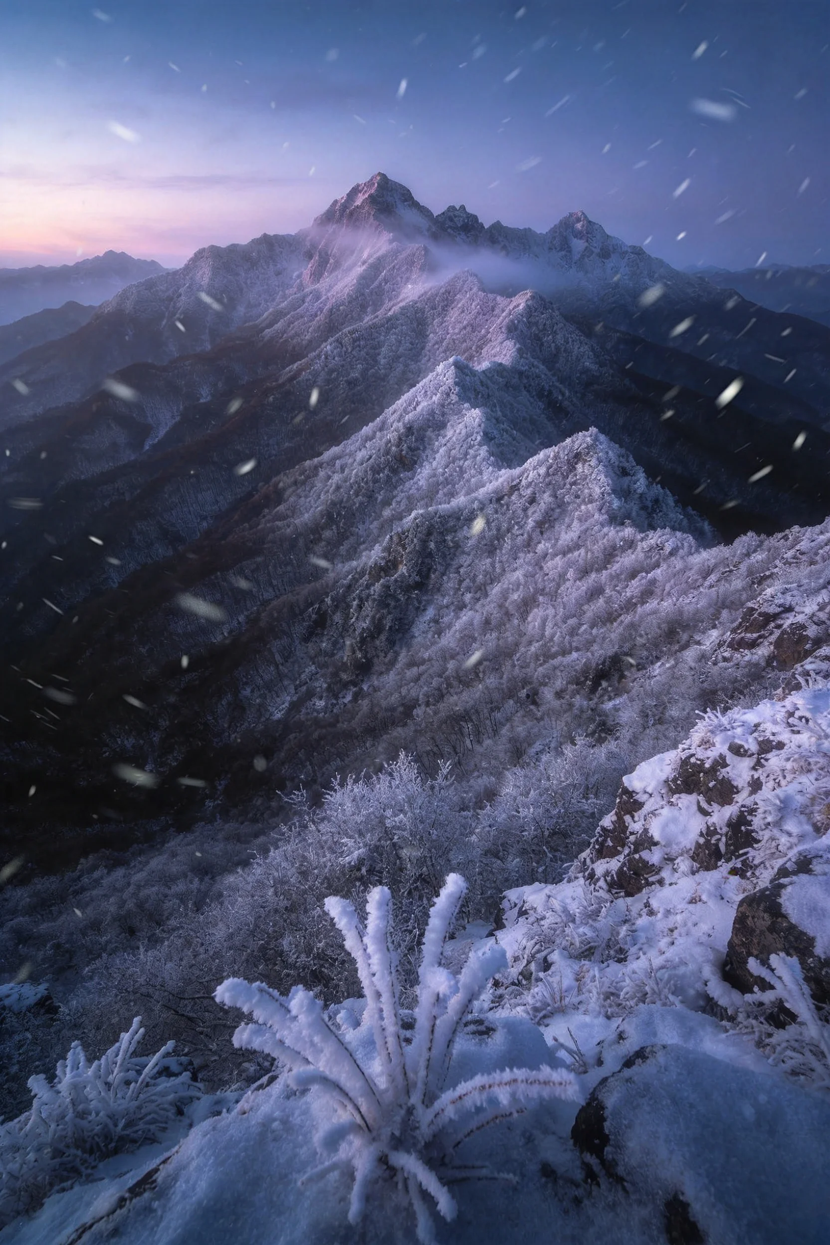 雪山山脉风光中,近处灌木被白雪覆盖,岩石表面形成清晰的冰晶结构,雪花纷飞,呈现出冬日雪景的独特质感。